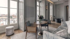 A modern living room with a round table, a sofa, and a large window offering a city view. - Verride Palácio Santa Catarina (Lisbon)