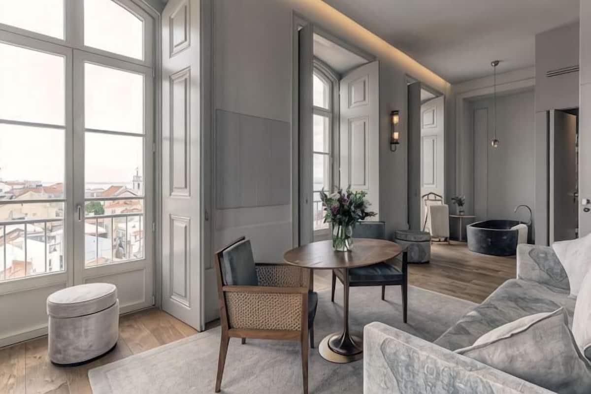 Una sala de estar moderna con una mesa redonda, un sofá y un ventanal con vistas a la ciudad.