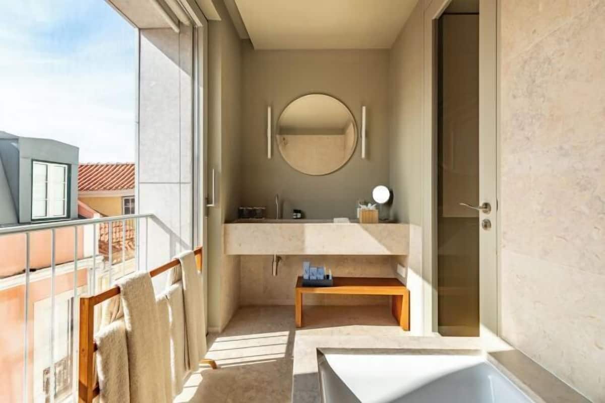 Un baño moderno con una bañera, un espejo redondo y un lavabo.