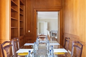 Una sala de conferencias con una larga mesa, sillas y botellas de agua.