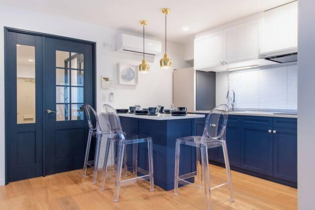 Una cocina con una isla central, taburetes de bar e iluminación colgante.
