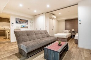 Ein modernes Wohnzimmer mit einer Couch, einem Couchtisch, einem Bett und einer Küchenzeile.
