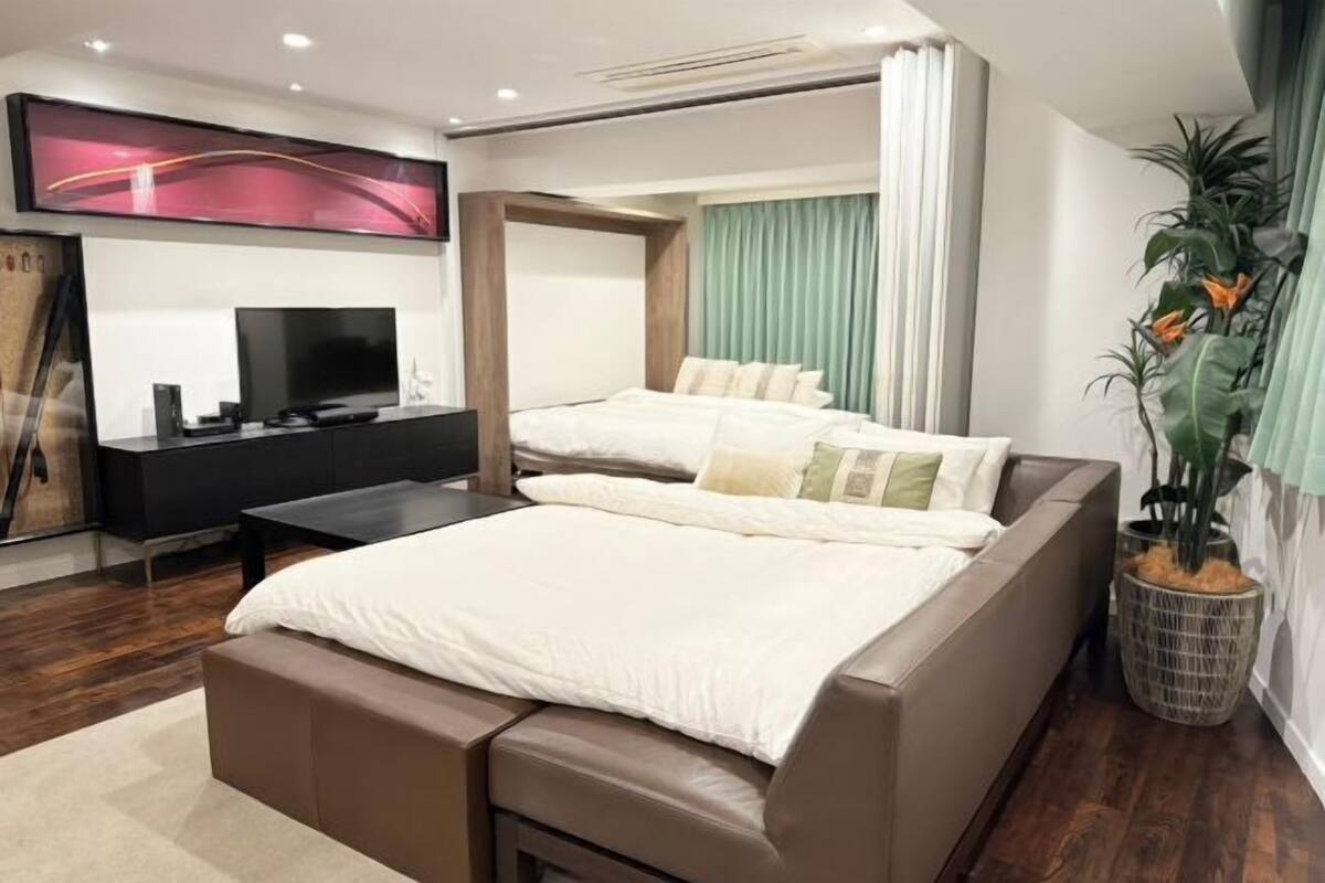 Una habitación de hotel moderna con una cama grande, un televisor, un escritorio y una planta en maceta.