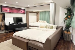 Ein modernes Hotelzimmer mit einem großen Bett, einem Fernseher, einem Schreibtisch und einer Topfpflanze.