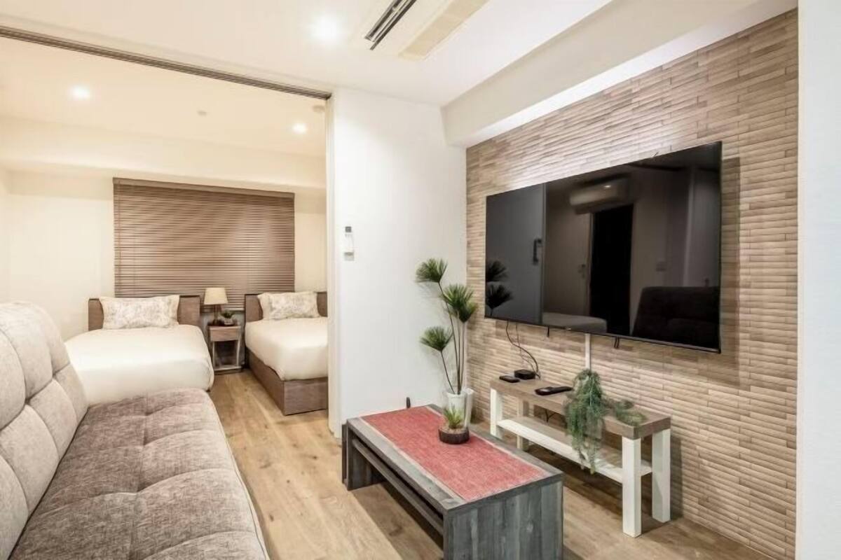 Una sala de estar moderna con un sofá, un televisor en la pared, una mesita y un banco.