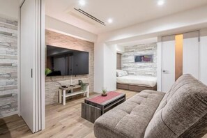 Un salon moderne doté d’un téléviseur à écran plat, d’un canapé, d’une table basse et d’un lit adossé à un mur en pierre.