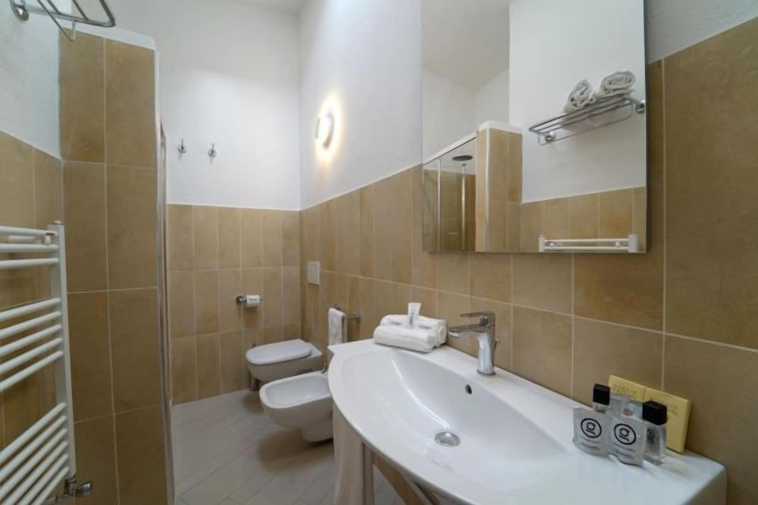 Een badkamer met een wastafel, spiegel, handdoekrek en toilet.