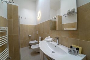 Ein Badezimmer mit Waschbecken, Spiegel, Handtuchhalter und Toilette.