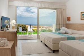 A hotel room with a bed, a desk, a chair, and a view of the sea.