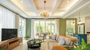A spacious living room with a TV, sofa, coffee table, and chandelier. - Viki Nest by SooBali 4BR (Bali)