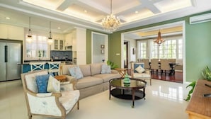 A spacious living room with a large sofa, a coffee table, and a dining area in the background. - Viki Nest by SooBali 4BR (Bali)