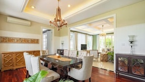 A spacious dining area with a large wooden table, white upholstered chairs, and a chandelier. - Viki Nest by SooBali 4BR (Bali)