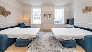 A bedroom with two beds, a large window, a TV, and a decorative wall piece. - Host & Stay Seel St Townhouse Apt II (Liverpool)