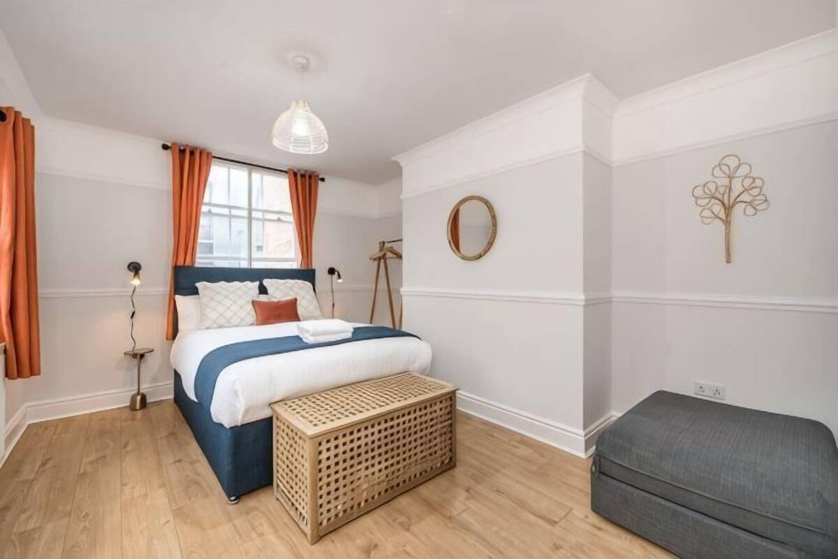Une chambre à coucher comprenant un lit, une table de chevet, une lampe et un miroir fixé au mur.