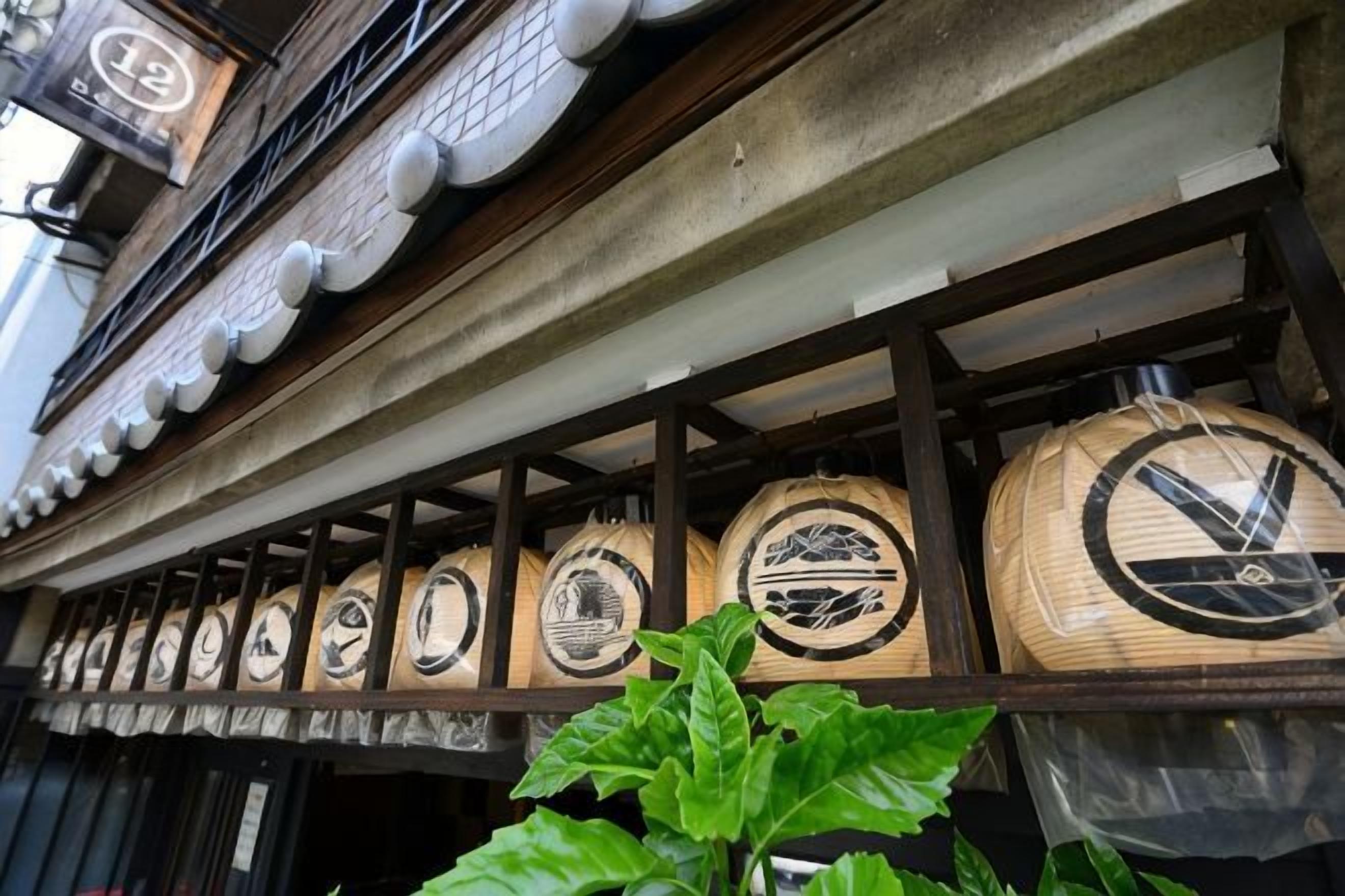 A row of traditional Japanese sake barrels mounted on a building's exterior wall.
