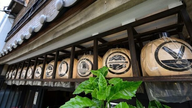 A row of traditional Japanese sake barrels mounted on a building's exterior wall. - Dozen Ryokan. over 100 years old.Cafe on the ground floor.550m from JR Kyoto station. (Kyoto)