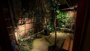 A dimly lit garden with a wooden fence, a pathway, and various plants.