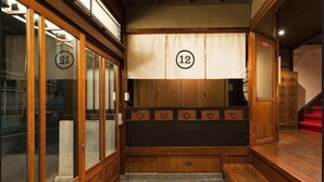 A traditional Japanese room with sliding doors, a tatami mat floor, and a wooden bench with a number sign.