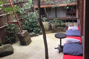 Een traditionele Japanse tuin met een zithoek met tatami matten, een klein tafeltje en een bamboestructuur.