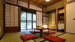 A traditional Japanese room with tatami flooring, a low table, and sliding doors. - Dozen Ryokan. over 100 years old.Cafe on the ground floor.550m from JR Kyoto station. (Kyoto)