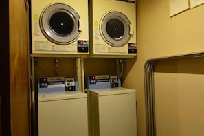 Een wasserette met twee gestapelde wasmachines en twee drogers.