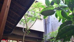 A traditional Japanese building with a wooden structure and a view of a tree.