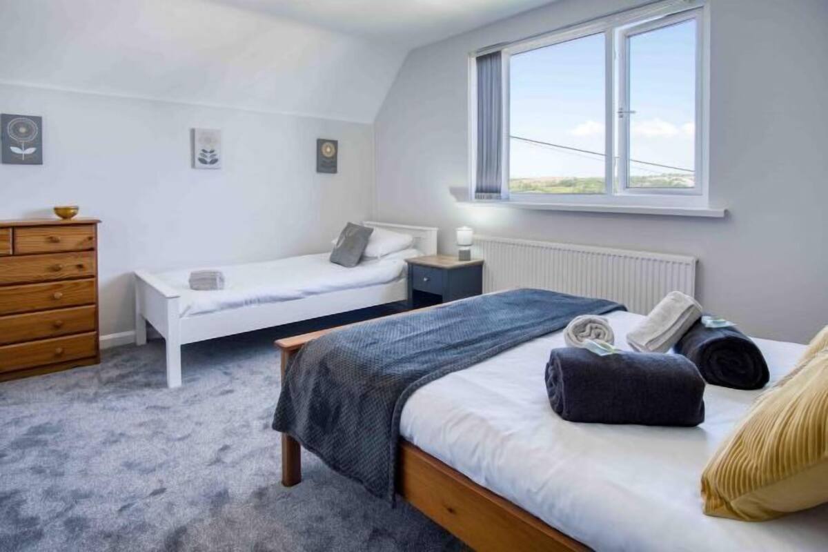 A bedroom with two beds, a dresser, a window, and a radiator.