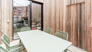 Un espace patio avec une table et des chaises, une porte-fenêtre coulissante et un mur en bois.