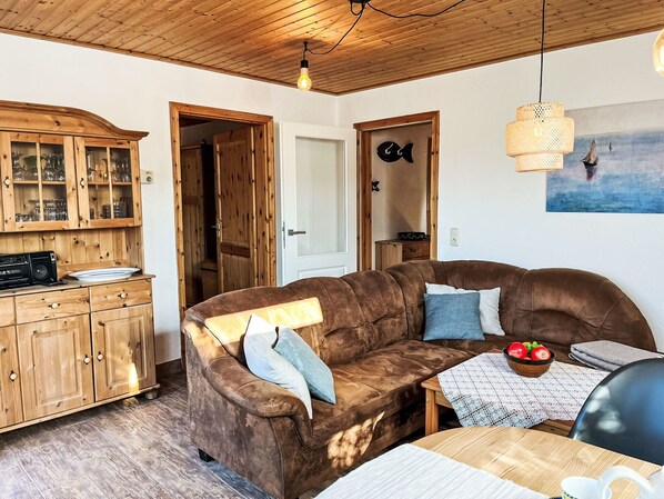 Una sala de estar acogedora con un sofá de cuero marrón, armarios de madera y un comedor con mesa y sillas.