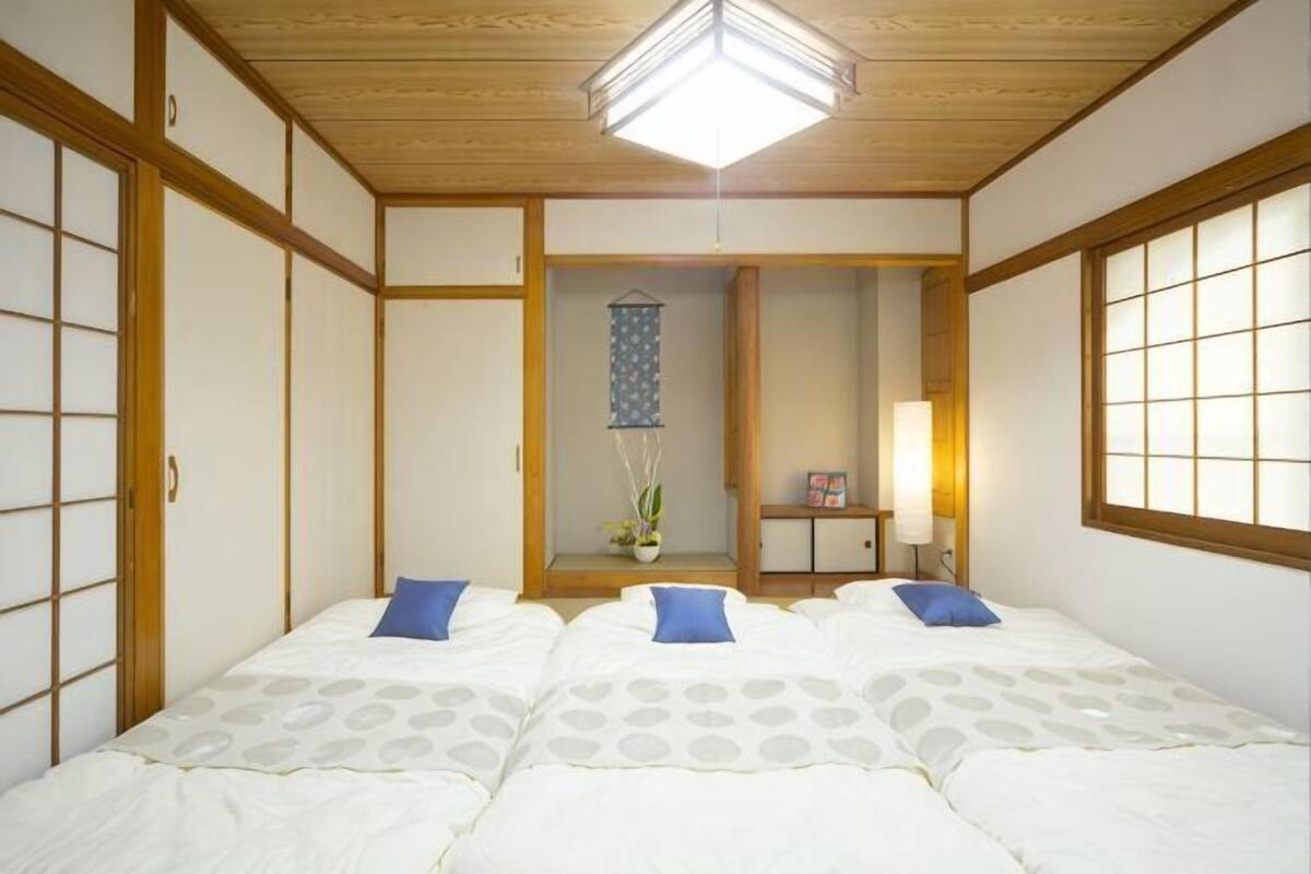 A traditional Japanese-style room with tatami flooring, a low ceiling, and a sliding door.