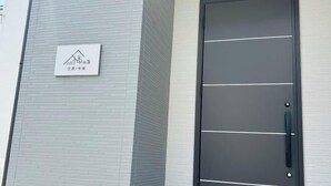 A modern building facade with a large black door and a sign with Japanese characters. - fukunosou kuukou1goutou (Fukuoka)