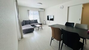A modern living room with a gray sofa, a small coffee table, and a dining table with chairs. - fukunosou kuukou1goutou (Fukuoka)