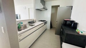 A compact kitchen with a stove, sink, and black countertop. - fukunosou kuukou1goutou (Fukuoka)