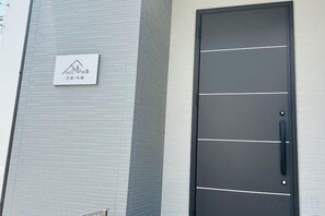 A modern building facade with a large door and a sign indicating a hotel or lodging establishment. - fukunosou kuukou1goutou (Fukuoka)