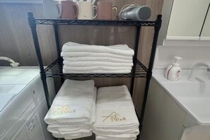 A shelf with folded towels and a bottle of hand sanitizer. - fukunosou kuukou1goutou (Fukuoka)