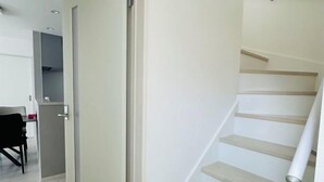 A modern interior with a staircase, a dining area, and a partially visible closet. - fukunosou kuukou1goutou (Fukuoka)