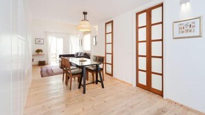 A modern interior with a dining area, wooden flooring, and a large sliding door. - Stylish Apt w/ Charming Balcony in the Very Center (Tel Aviv)