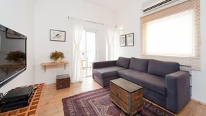 A modern living room with a grey sofa, a wooden coffee table, and a patterned rug. - Stylish Apt w/ Charming Balcony in the Very Center (Tel Aviv)