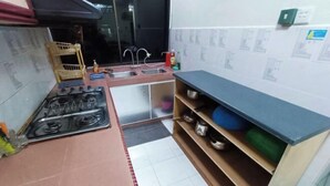 A compact kitchen with a gas stove, sink, and a small countertop. - Kota 3BR Townhouse 5 Pax - TVBox/Mahjong/Jonker (Melaka)