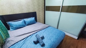 A bed with a blue bedspread, a grey blanket, and a blue pillow. - Kota 3BR Townhouse 5 Pax - TVBox/Mahjong/Jonker (Melaka)