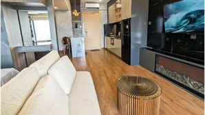 Una sala de estar moderna con un sofá, una mesa redonda de madera y un televisor de pantalla plana grande montado en la pared.
