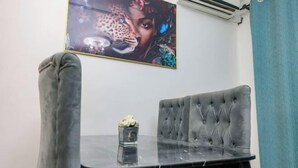 A room with a tufted grey sofa, a glass table with a vase, and a leopard-themed artwork on the wall. - T-Square Residence Makepe (Douala)