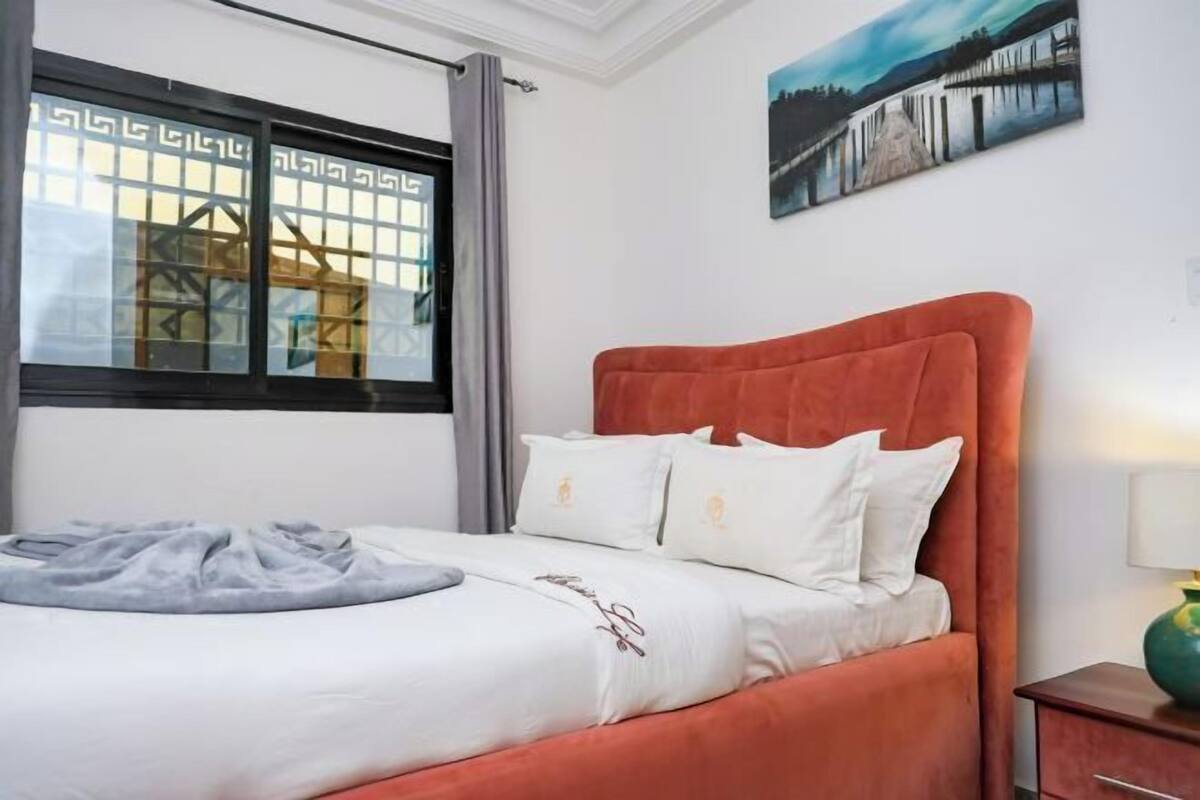 Une chambre d’hôtel avec un lit, une fenêtre donnant sur un beau paysage et un tableau accroché au mur.