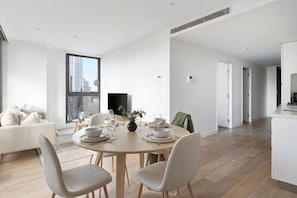 A modern dining area with a round table, chairs, and a city view. - A Cozy Apt with City Views Near Crown Casino (Southbank)