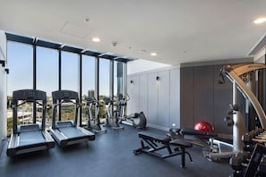 Et fitnesscenter med løbebånd, crosstrainere og træningsudstyr.