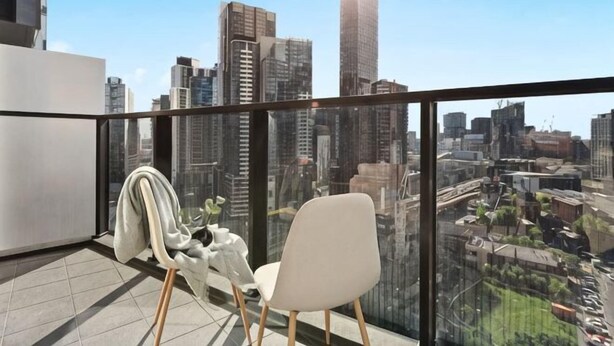 A balcony with a city view, a chair, and a coat rack. - A Cozy Apt with City Views Near Crown Casino (Southbank)