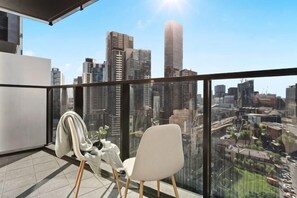 A balcony with a city view, a chair, and a coat rack. - A Cozy Apt with City Views Near Crown Casino (Southbank)