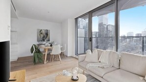 A modern living room with a sofa, coffee table, and dining area. - A Cozy Apt with City Views Near Crown Casino (Southbank)