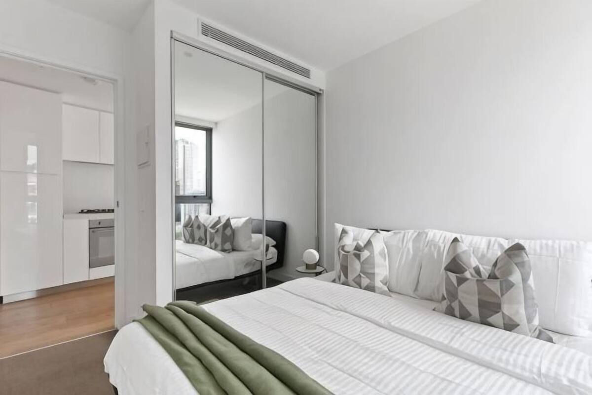 Ein modernes Schlafzimmer mit einem großen Bett, einem Kleiderschrank und einem Spiegel.