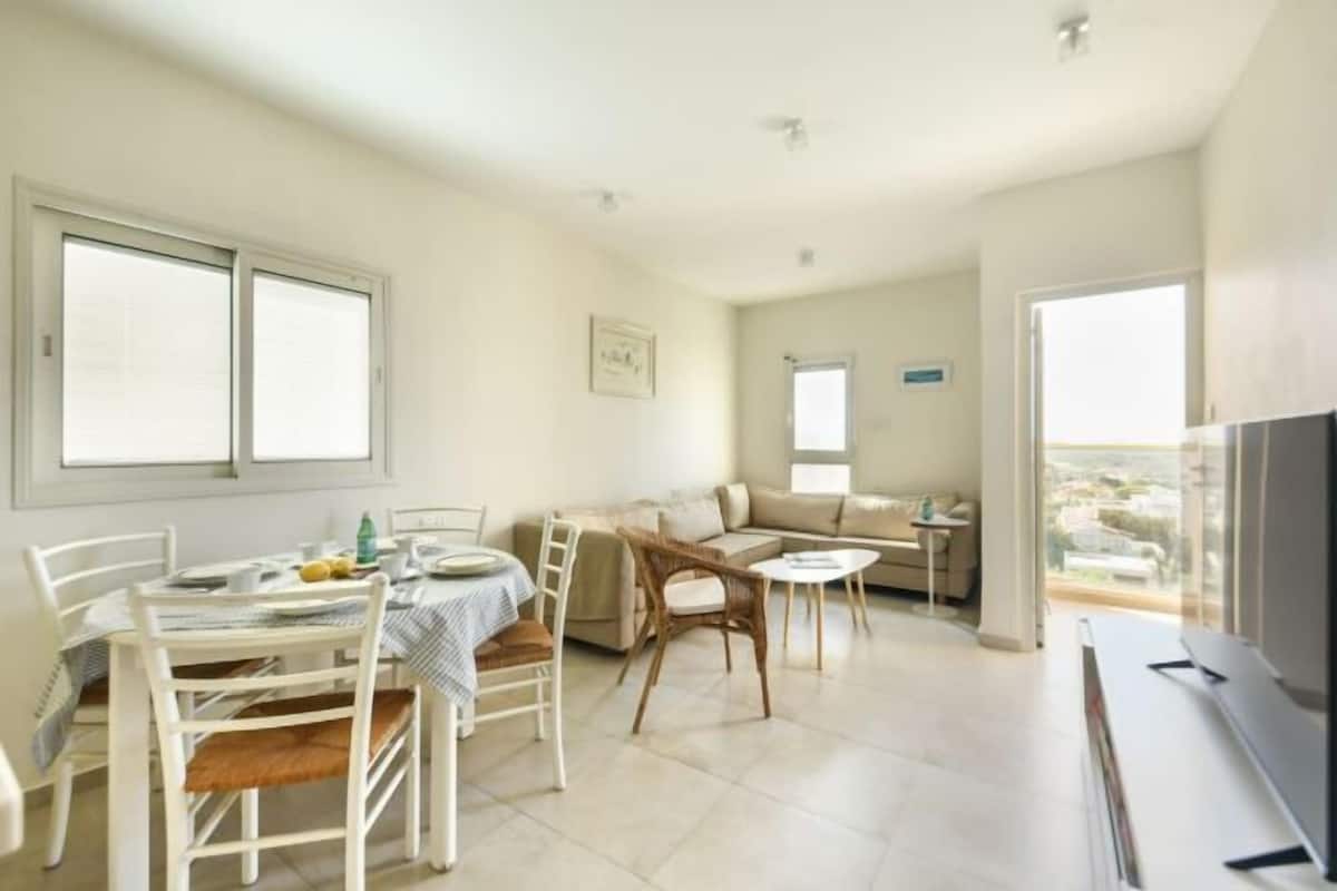 Un amplio espacio de sala con una mesa de comedor, sillas, un sofá y una televisión.